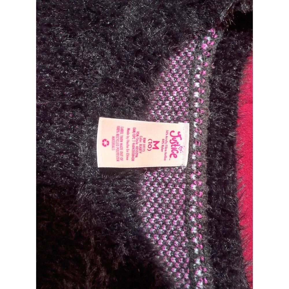 This is a Justice girls' black fuzzy eyelash sweater featuring pink and blue...